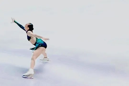 mayuko oka skating the part of her 'peacock' short program from 2025-26 season where she leans forward with her feet spread and puts her hands to the ice, turning her head toward the judges