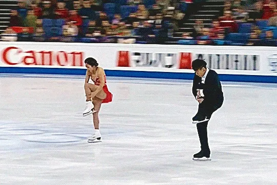 pairs figure skaters wenjing sui and cong han skating at worlds 2017. they each extend one leg out and spread their arms in a choreographic move